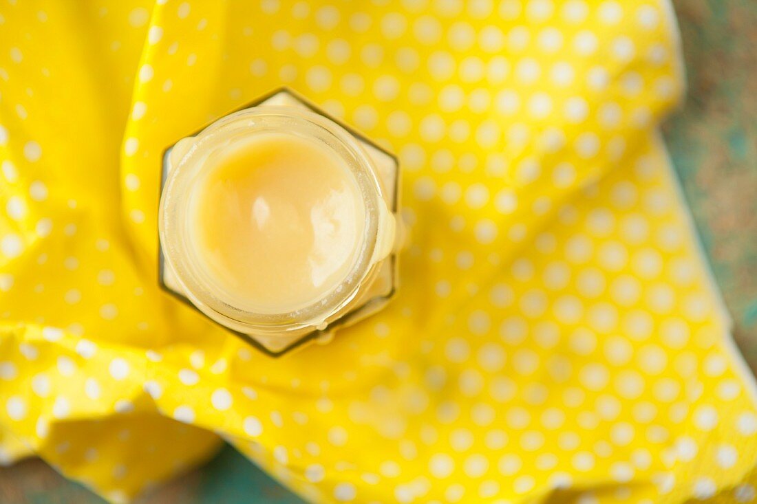 Hausgemachte Zitronencreme im Glas auf gelbem Tuch