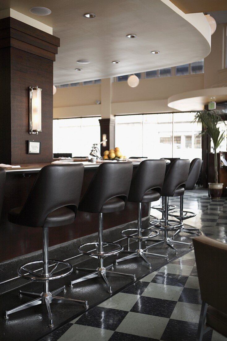 A restaurant bar with black leather stools