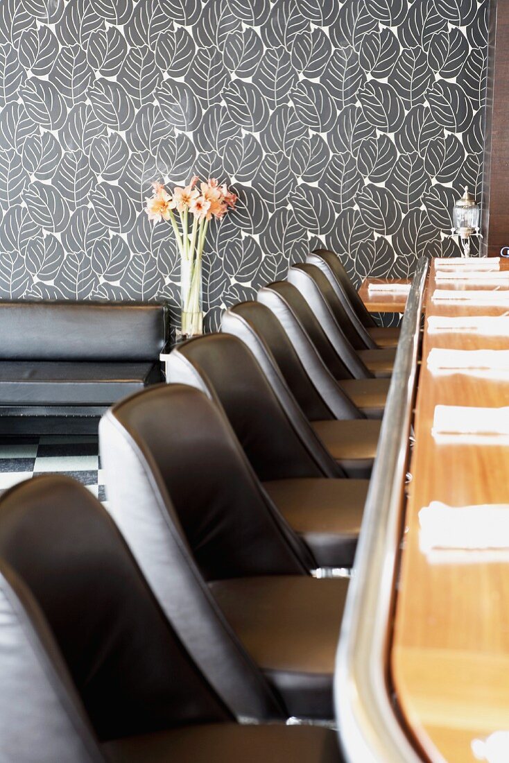 Bar counter with black leather stools in restaurant