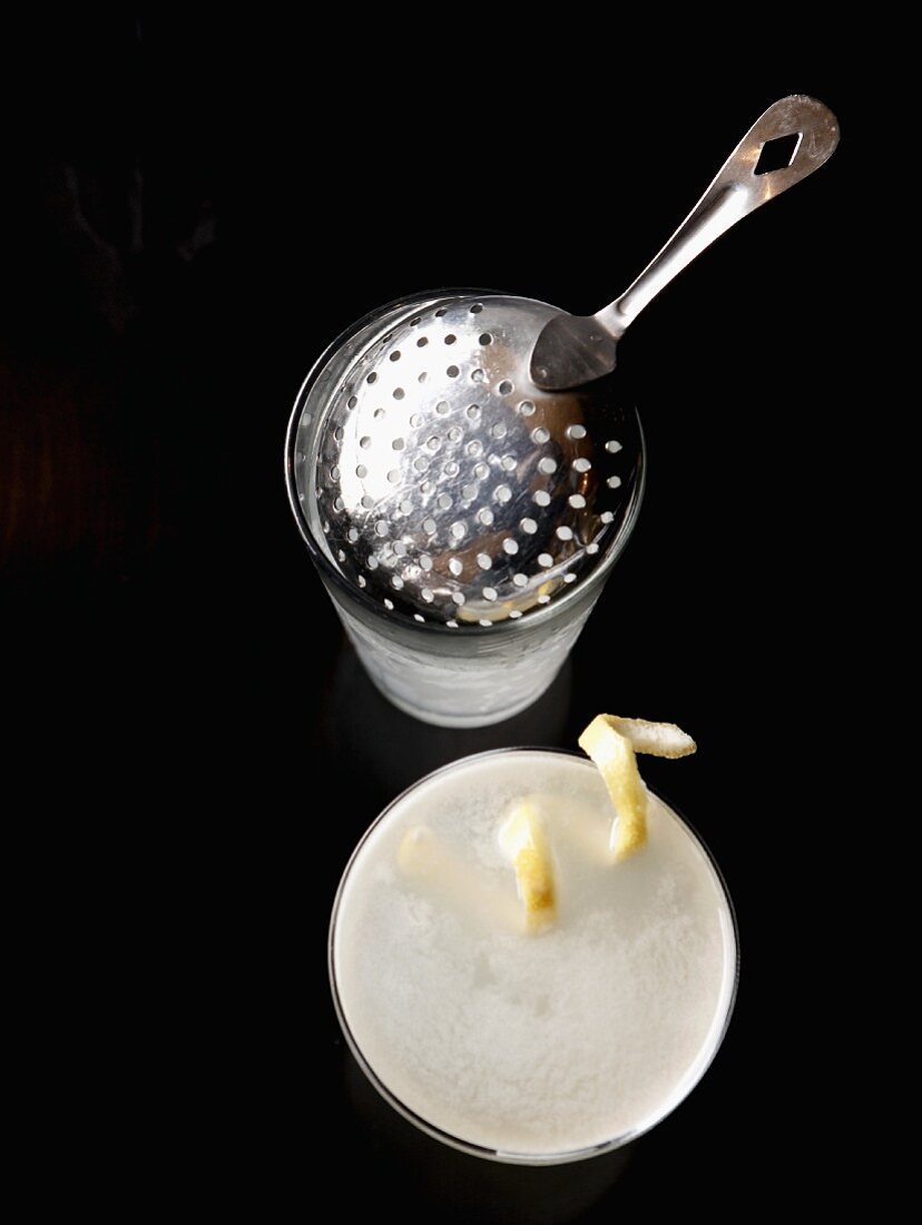 Lemon Drop cocktail with lemon zest, a shaker and bar sieve