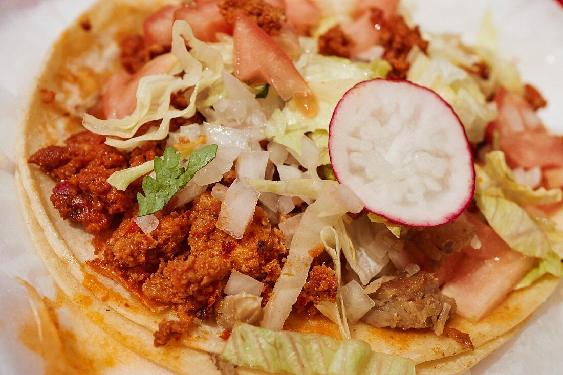 A taco with chorizo, radishes and lettuce