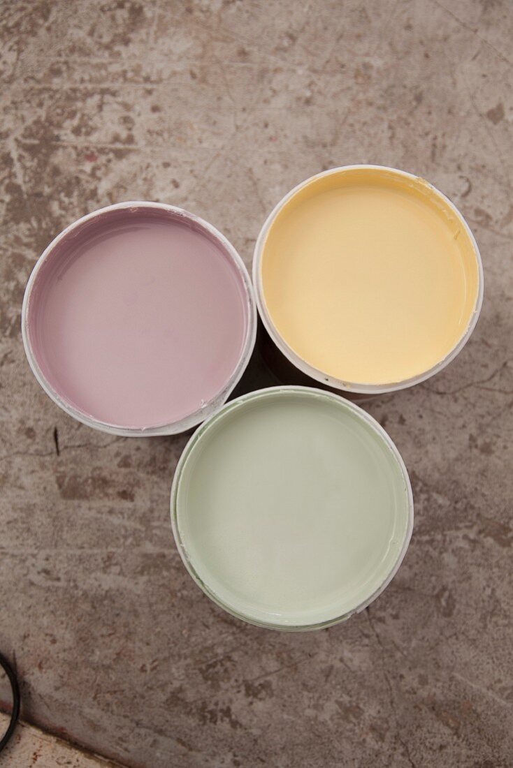 View down onto three open pots of pastel paints