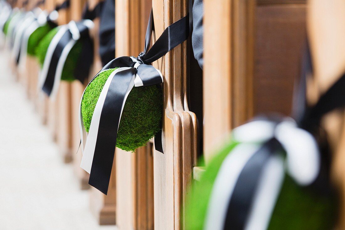 Baubles tied to church pews with ribbons as wedding decorations