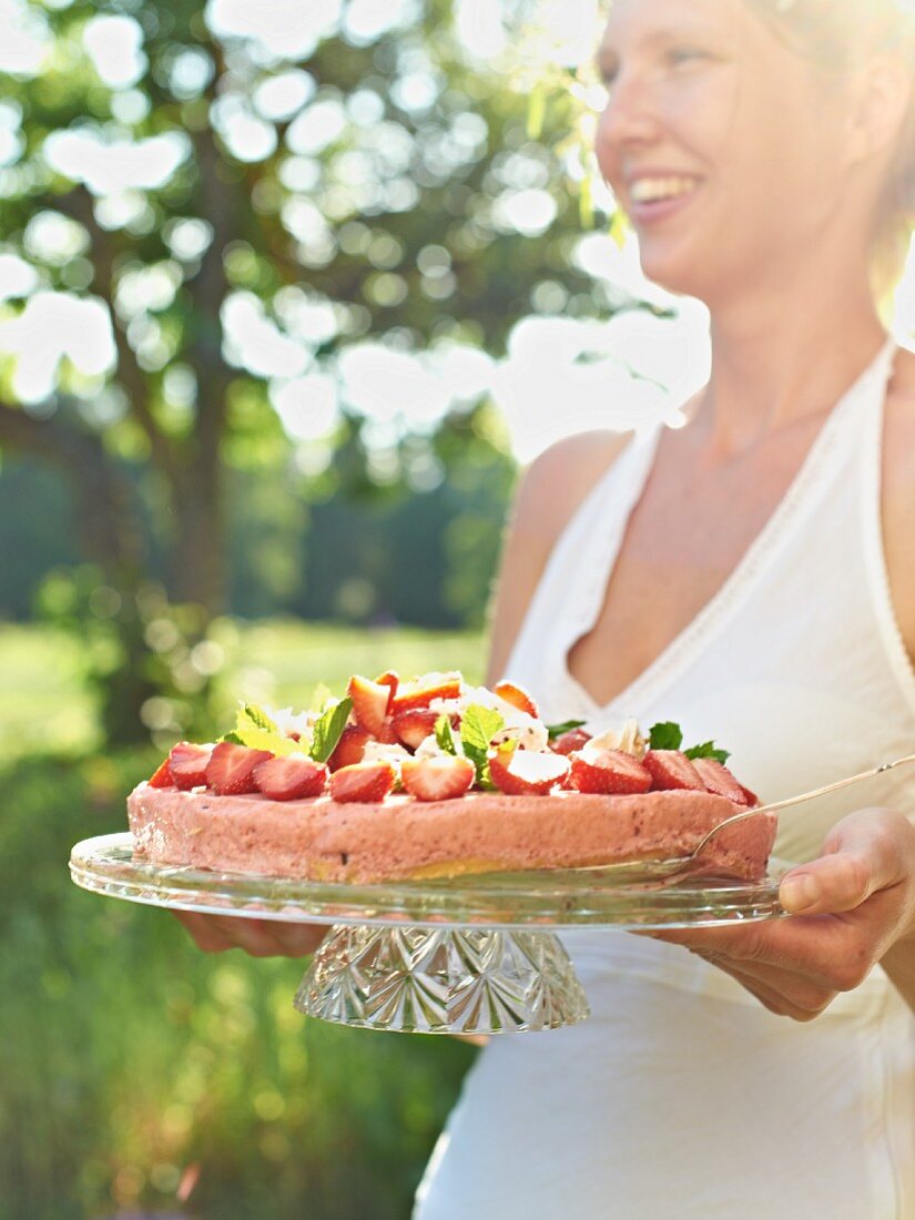 A woman serving a strawberry tart at a garden party