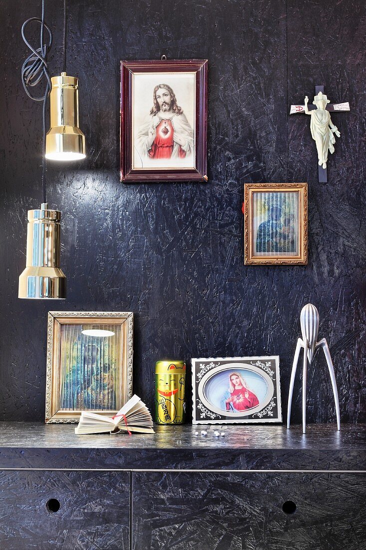 Black-painted chipboard panels on walls and kitchen cupboards, religious icons and pendant lampa