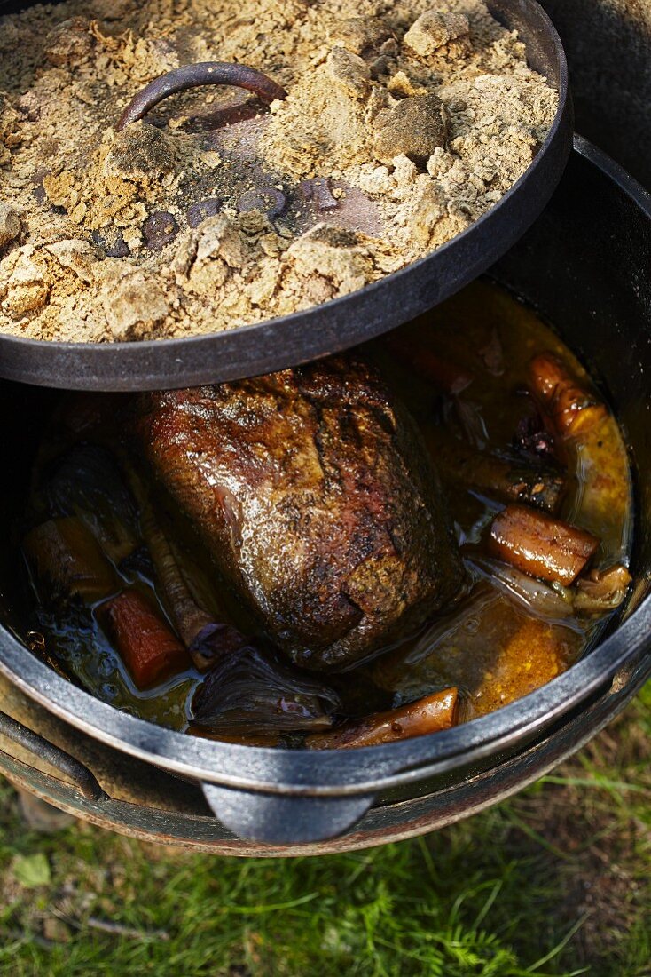 Braised roast pork with vegetables being made in a Dutch oven