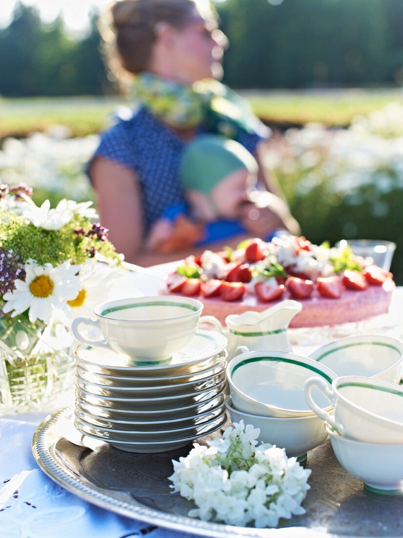 Strawberry tart and teacups on a garden table