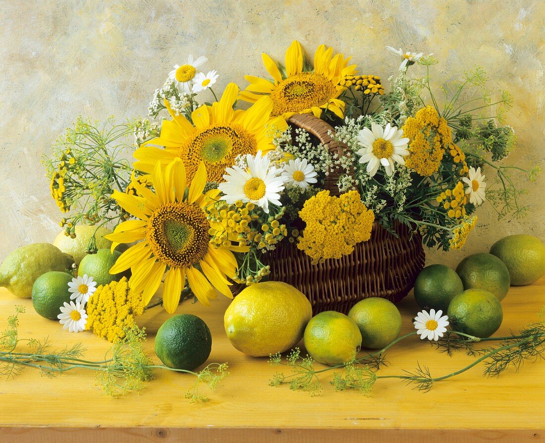An arrangement of citrus fruits and yellow summer flowers in a wicker basket