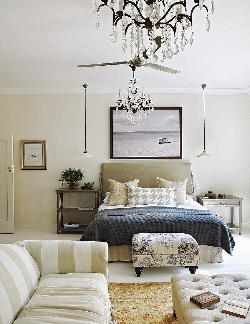 Striped sofa and footstool at foot of bed in elegant bedroom in mixture of patterns