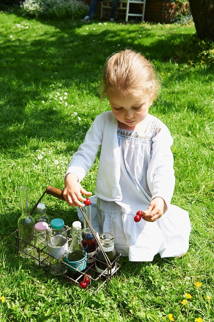 A little girl playing with cherries in a garden