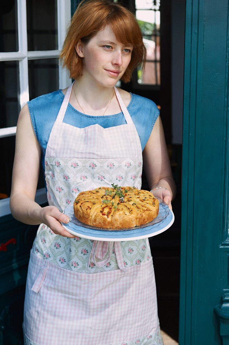 A woman serving a courgette and tomato rose cake