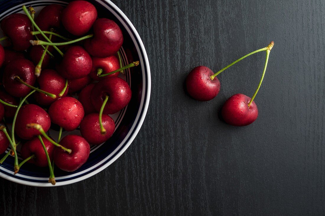 Cherries in a metal bowl on a black table