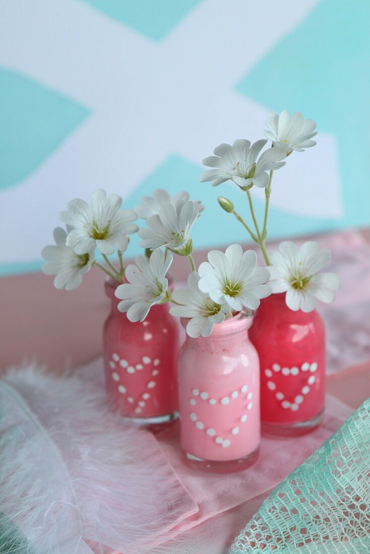 Small glass bottles painted with polka-dot hearts used as vases