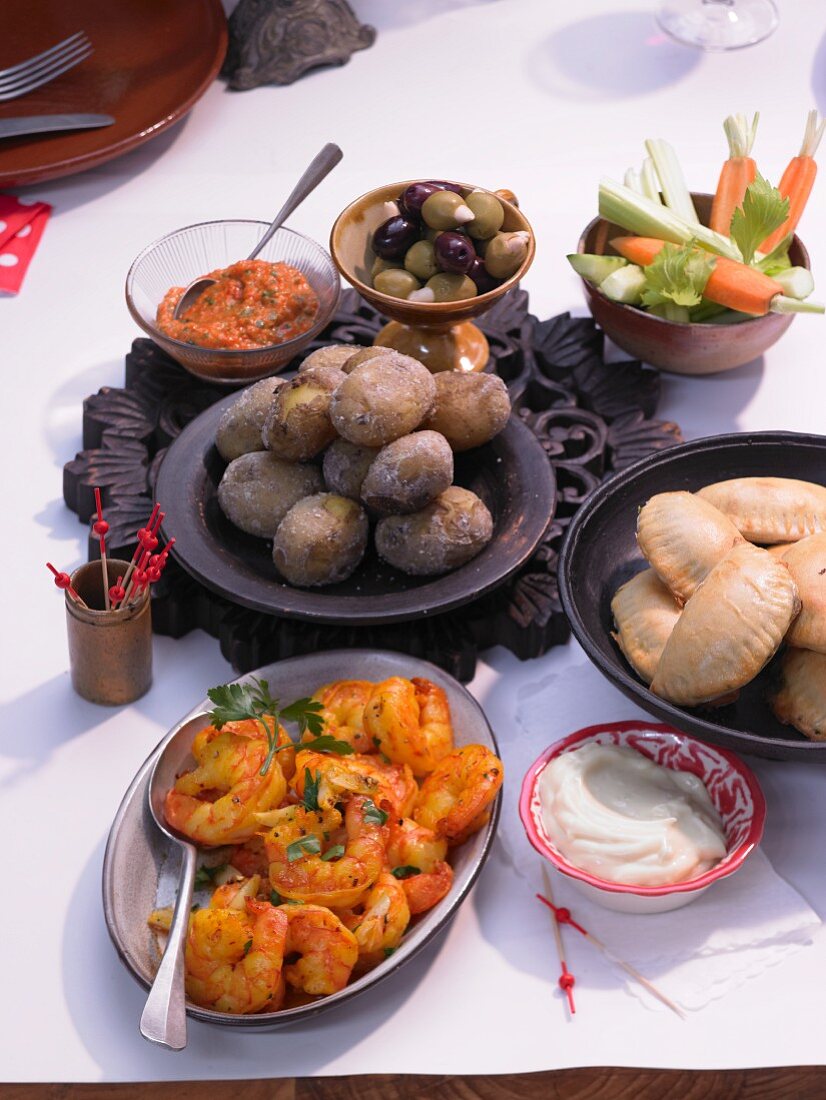 Aioli and mojo with salted potatoes, vegetable sticks, empanadas and saffron prawns