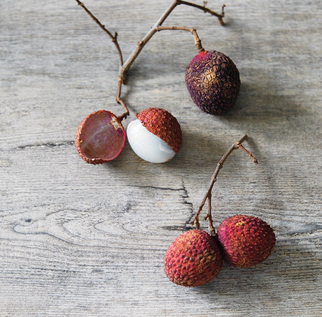 Lychees on twigs on a wooden surface