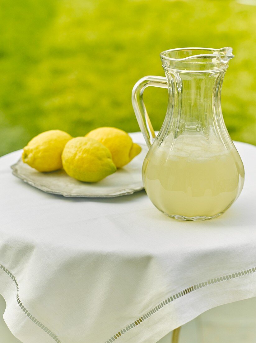 Zitronenlimonade im Krug auf Tisch im Freien