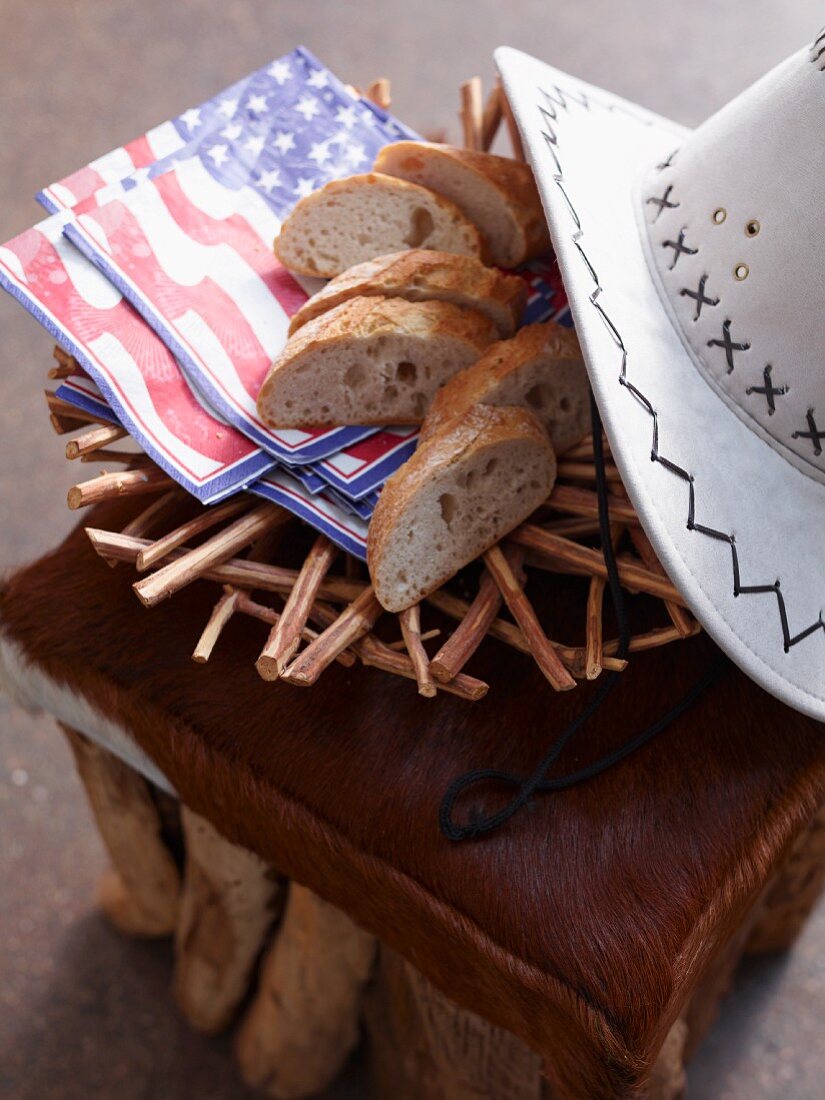 Geschnittenes Weißbrot mit Servietten & Cowboyhut auf Tierfellhocker