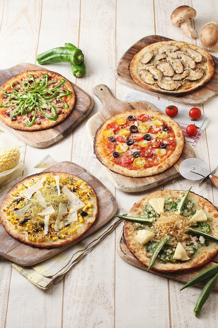 Five different vegetarian pizzas on wooden boards