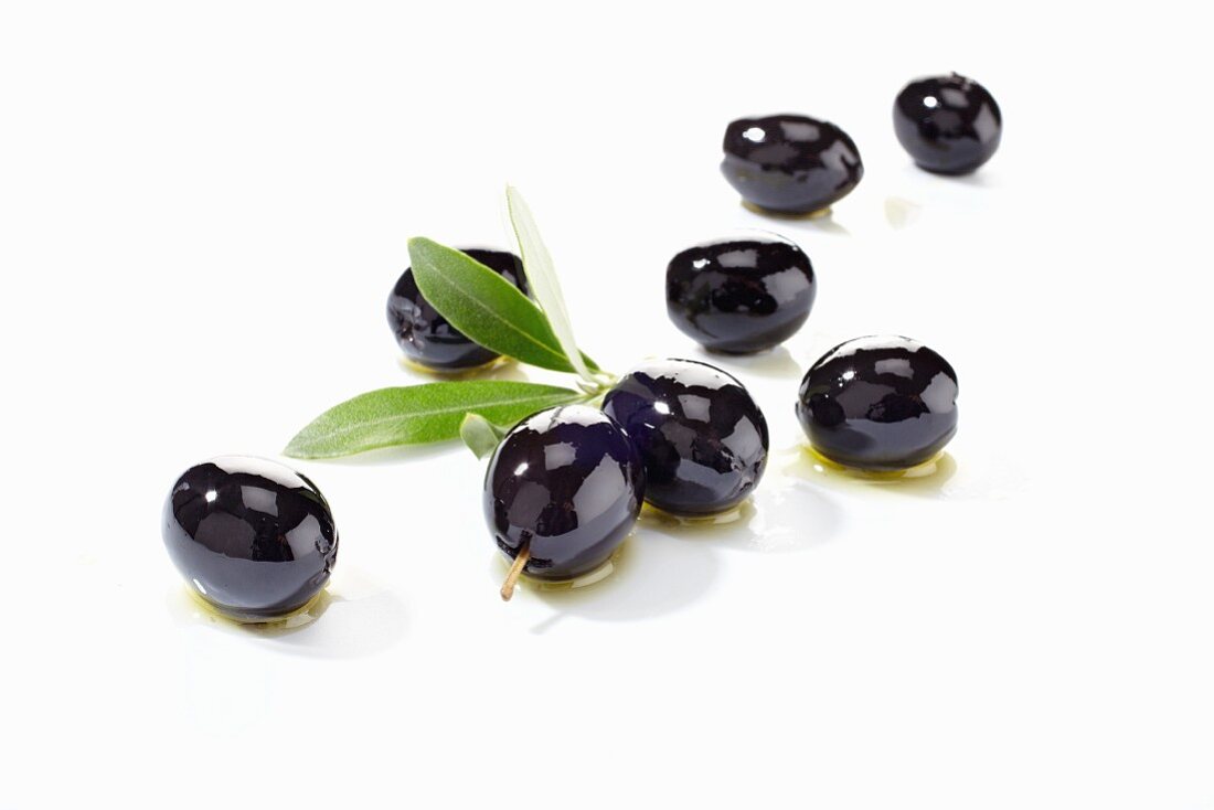 Mehrere schwarze Oliven mit Olivenöl