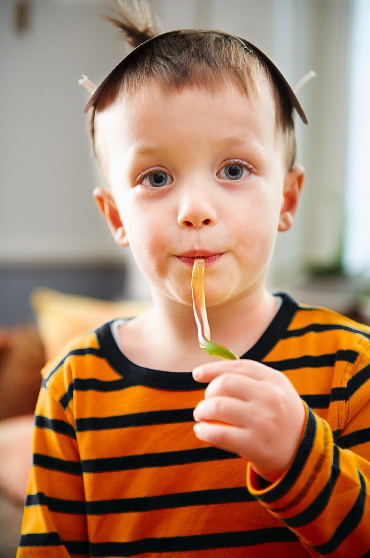 A little boy eating a jelly snake