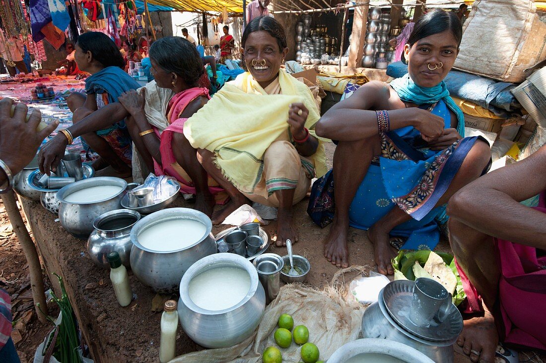 Lächelnde Mali-Frauen mit Goldnasenringen beim Verkauf von Joghurt aus Metalltöpfen auf einem Wochenmarkt, Guneipada, Orissa, Indien