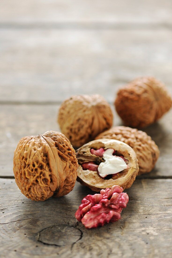 Red walnuts, whole and halved, on a wooden surface
