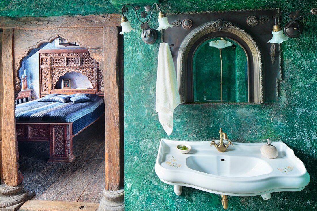 Sink on green, sponged wall next to open door with carved wooden frame and view into bedroom
