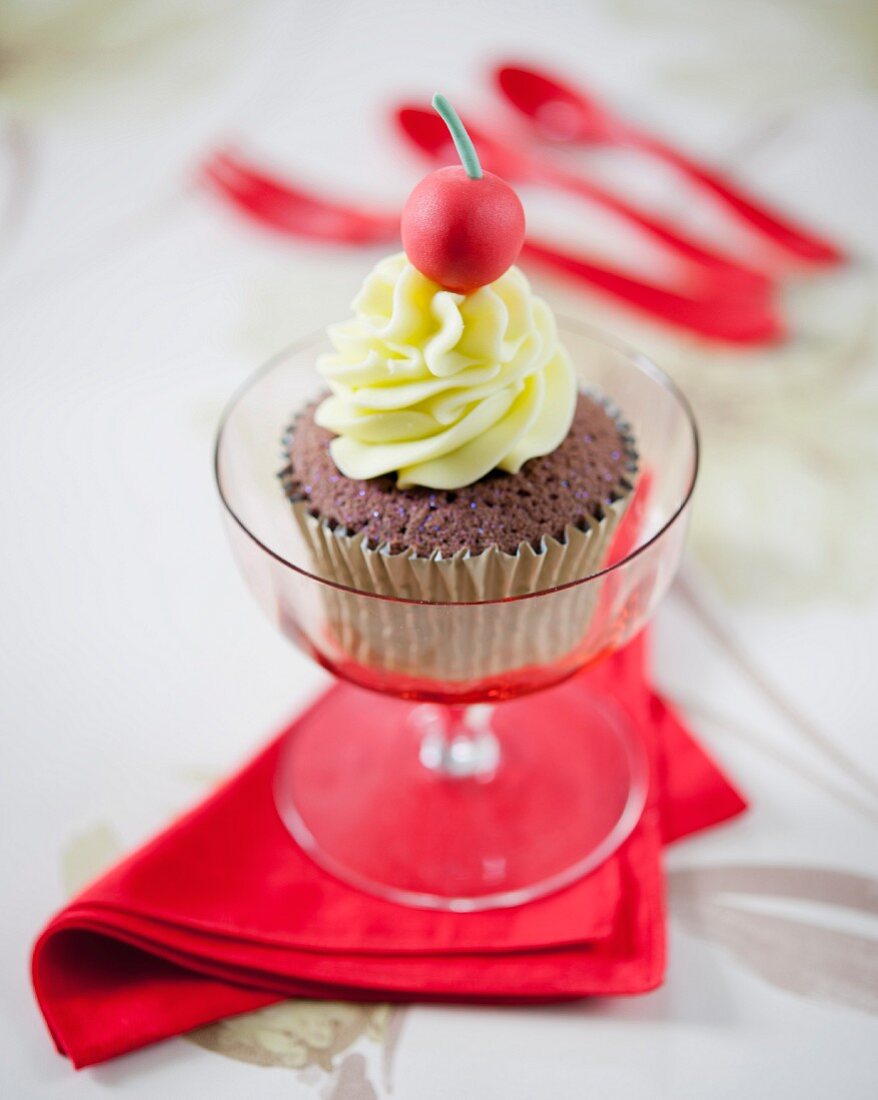 A chocolate cupcake decorated with a fondant cherry