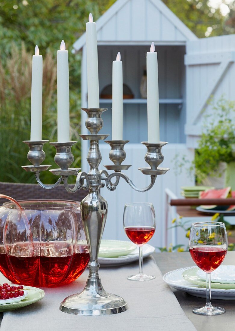 Kerzenleuchter mit Led-Kerzen und Bowlenglas auf gedecktem Gartentisch