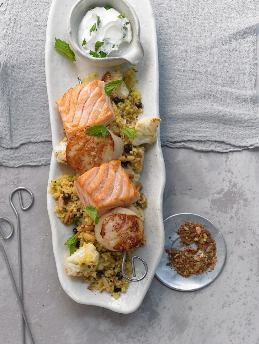 Salmon and scallops skewers on couscous with currants and pine nuts