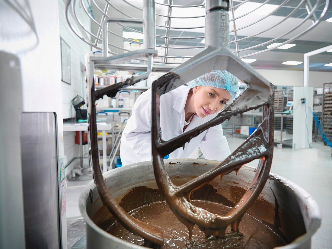A baker mixing chocolate in a cake factory