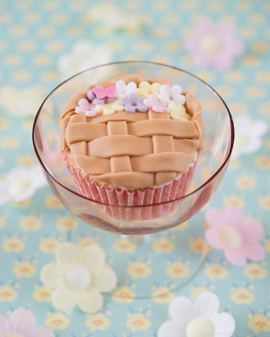 A flower basket cupcake decorated with fondant