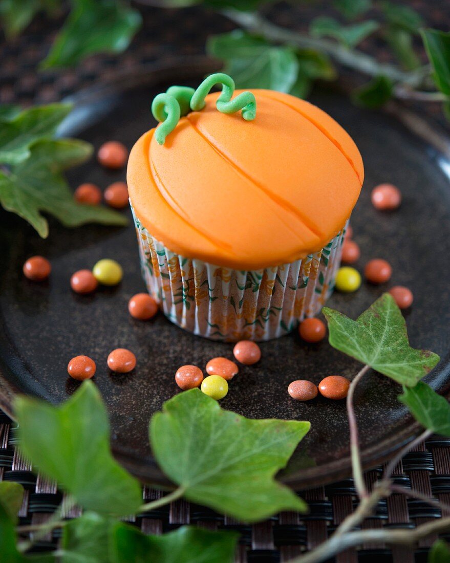 A pumpkin and cinnamon cupcake decorated with fondant icing for Halloween
