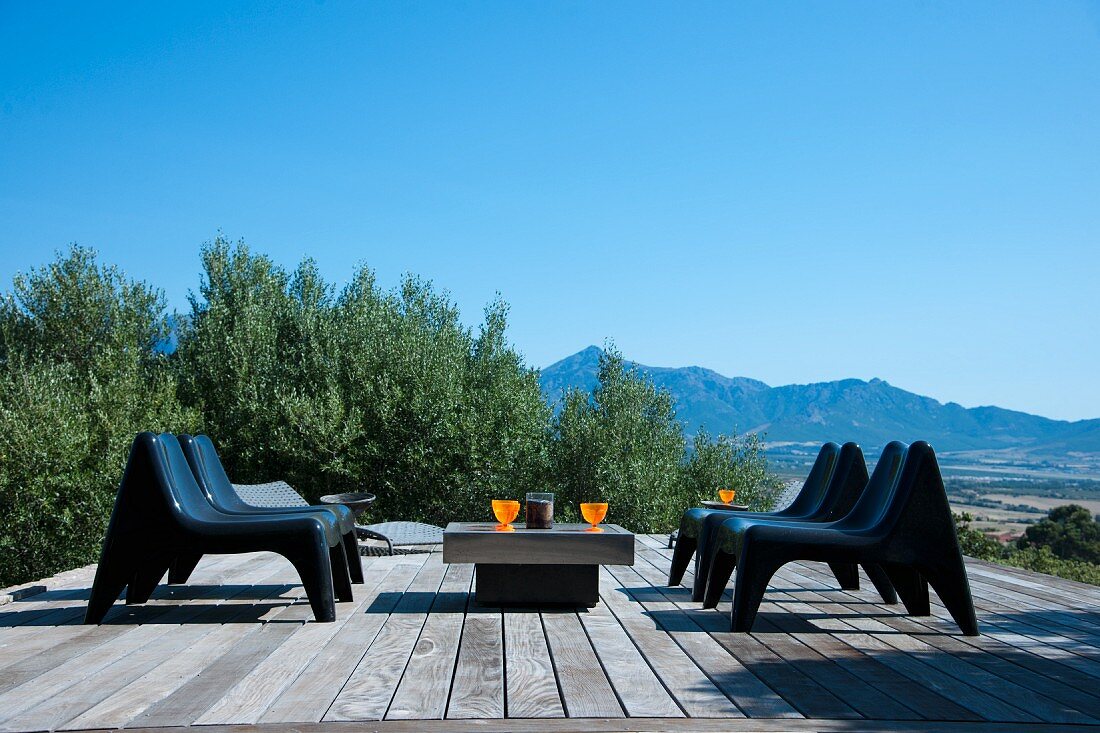 Modern seating group on wooden terrace surrounded by olive trees and fantastic panoramic view