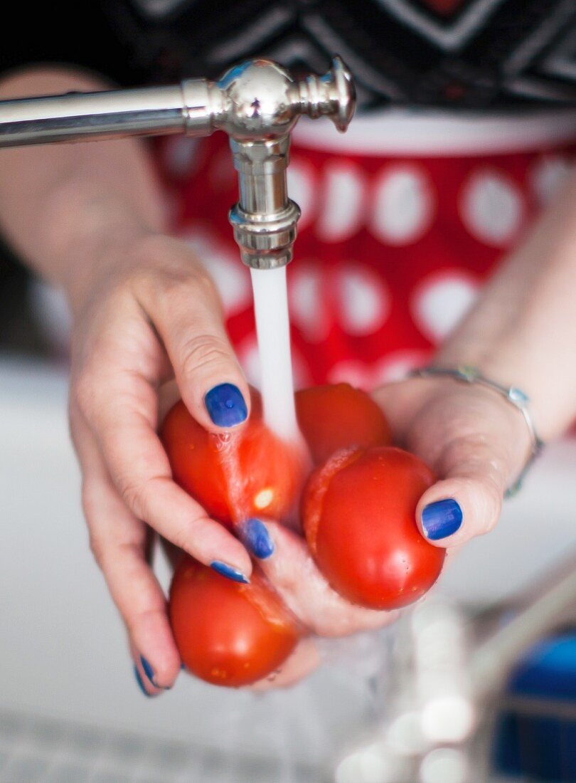 A woman washing tomatoes in a sink