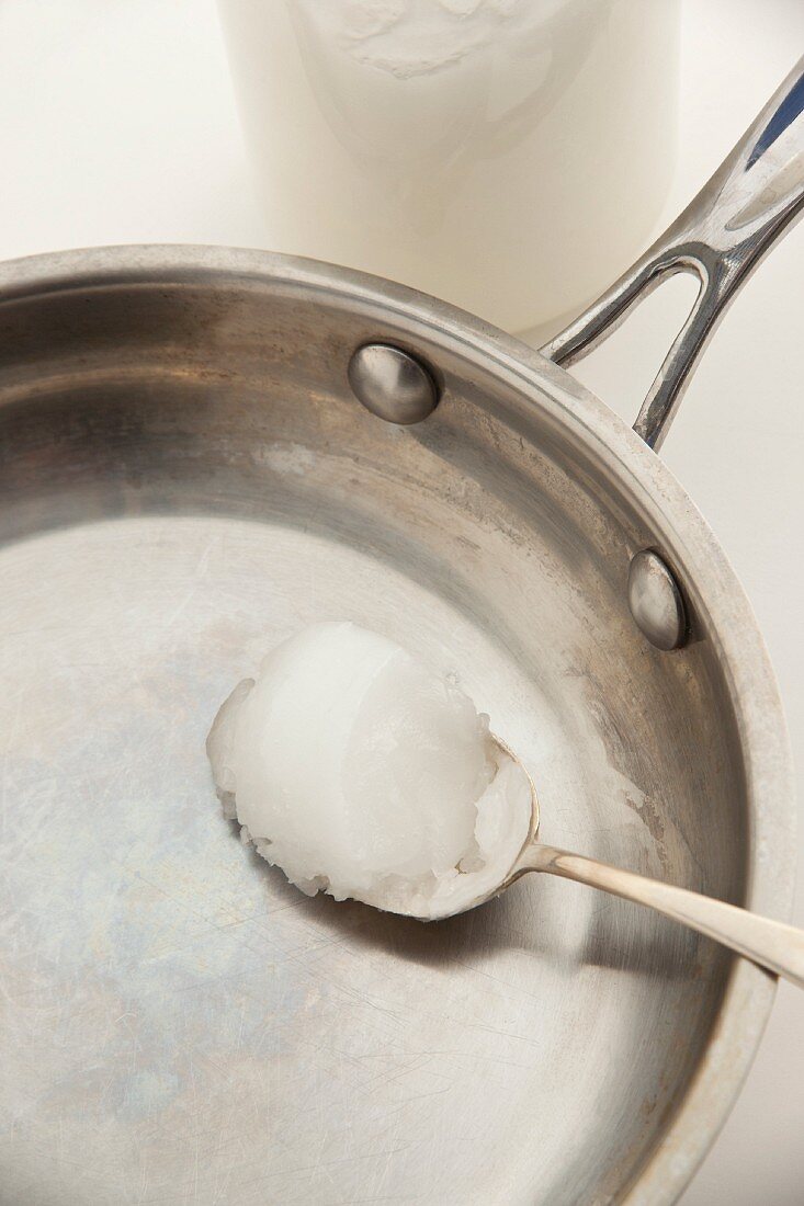 A spoonful of coconut fat in a frying pan