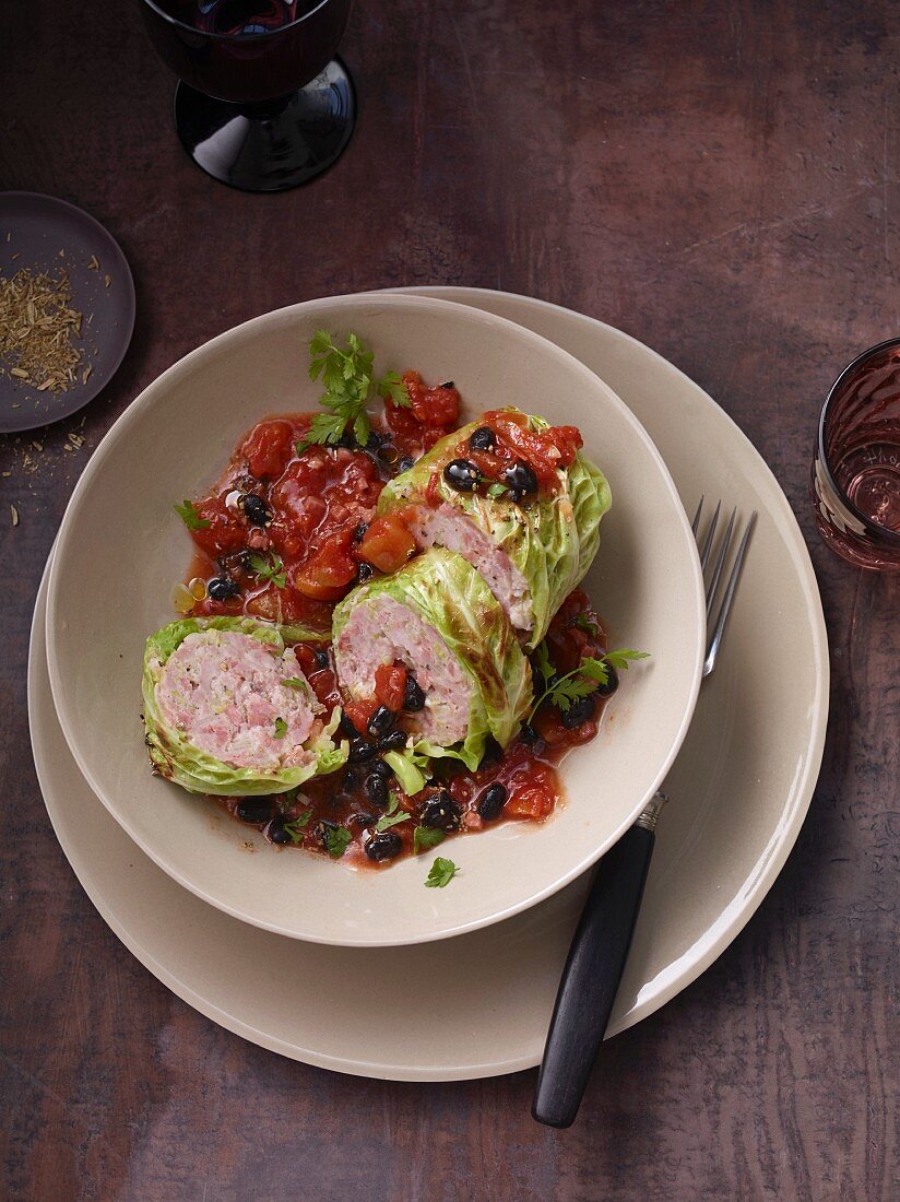 Krautwickel vom Wirsing mit Salsiccia auf schwarzem Bohnenragout