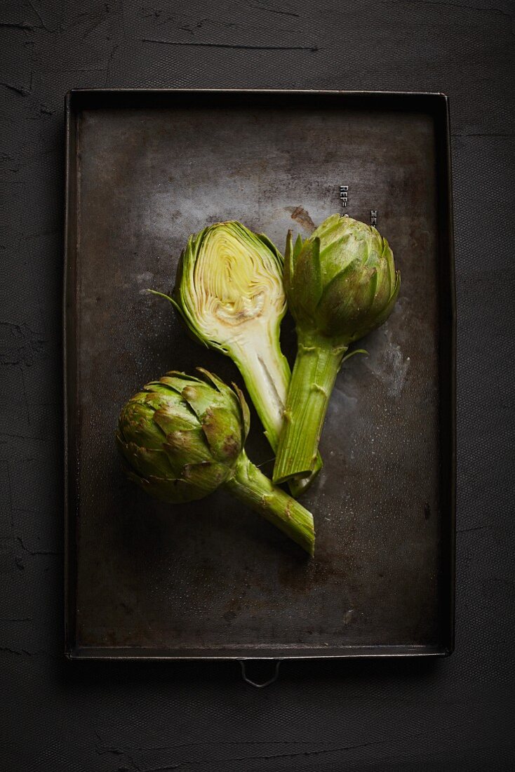 Artichokes on a black baking tray (seen from above)