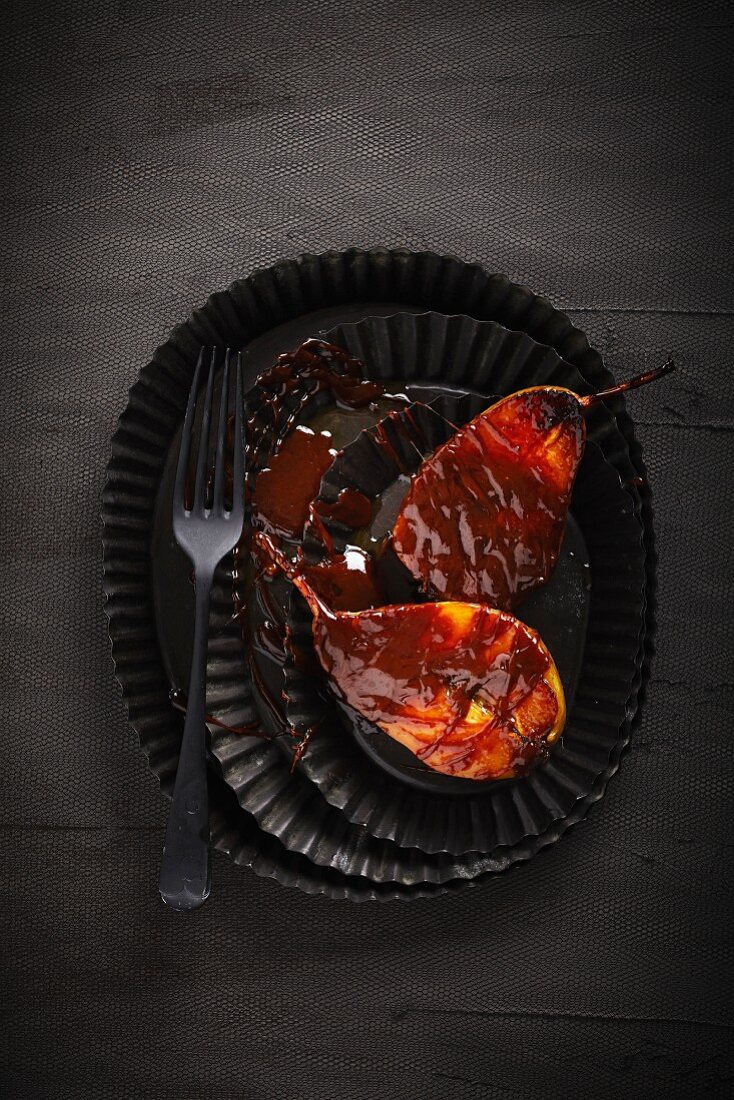 Chocolate-glazed pears on a black plate (seen from above)
