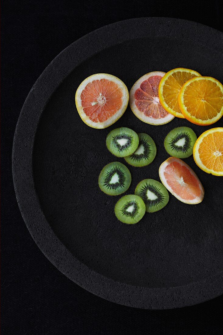 Grapefruit-, Orangen- & Kiwischeiben auf schwarzem Teller