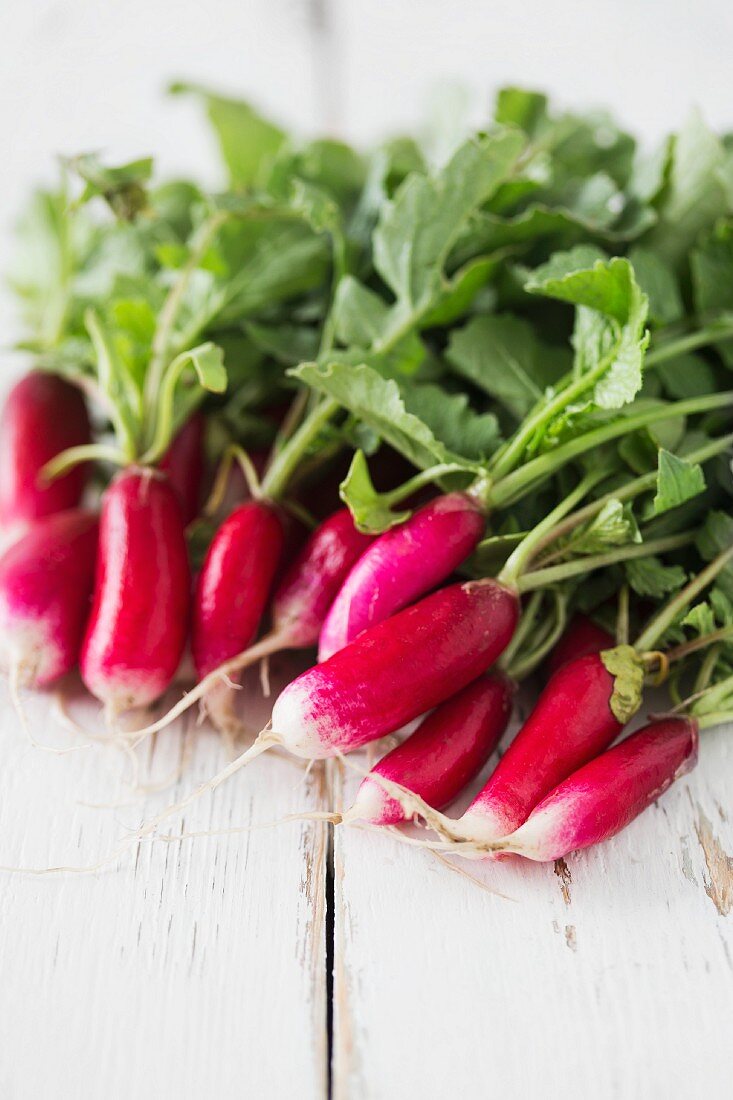 Radishes with leaves on a white wooden surface