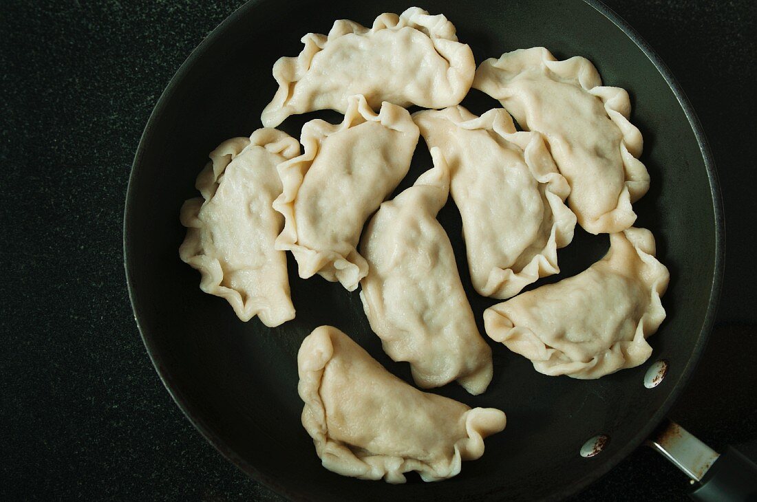 Gekochte Pierogi (Teigtäschchen mit Fleischfüllung, Polen) in Bratpfanne