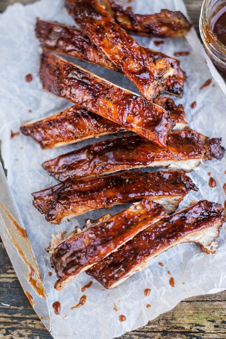 Spicy pork ribs with Bourbon barbecue sauce on paper (close-up)