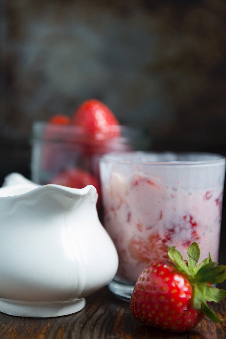 Strawberries with cream in a glass, fresh strawberries and a jug of cream