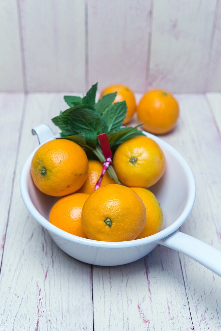 Oranges in an enamel colander with fresh mint