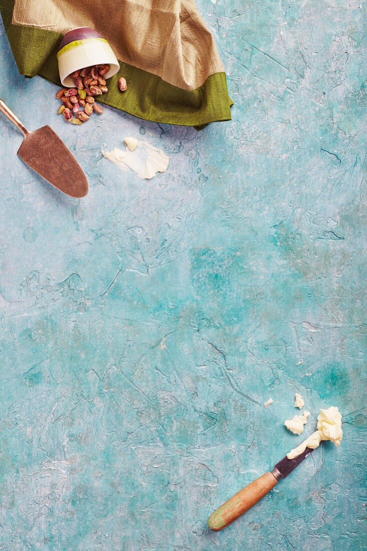 Bowls of pistachios, a cake slice and a knife with crème fraîche