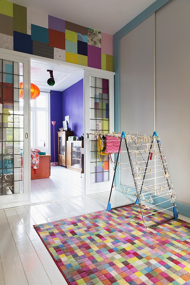Laundry rack on colourful rug in front of glass sliding doors