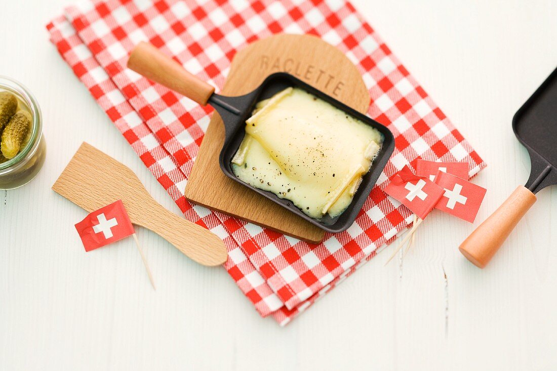 Raclette cheese in pans and black flags