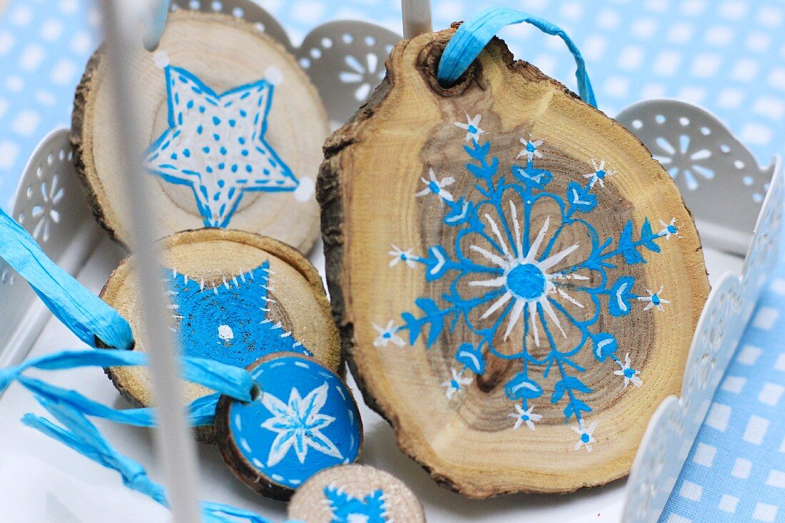 Kleine Baumscheiben als Weihnachtsdekoration, bemalt mit blau-weißem Sternenmotiv