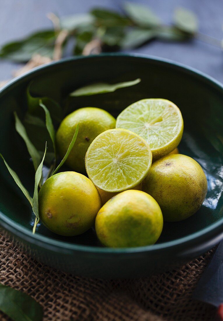 Limes, whole and halved, in a bowl